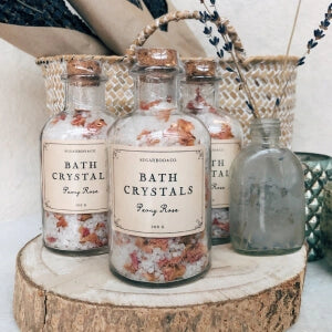 Bath crystals in glass bottles on wooden table.