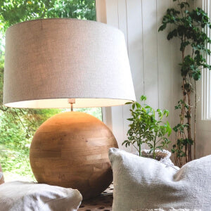 A wooden lamp with a white shade on a table.